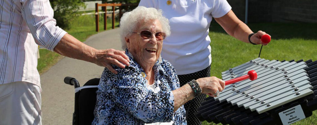 Une dame âgée joue du xylophone dans un parc aménagé